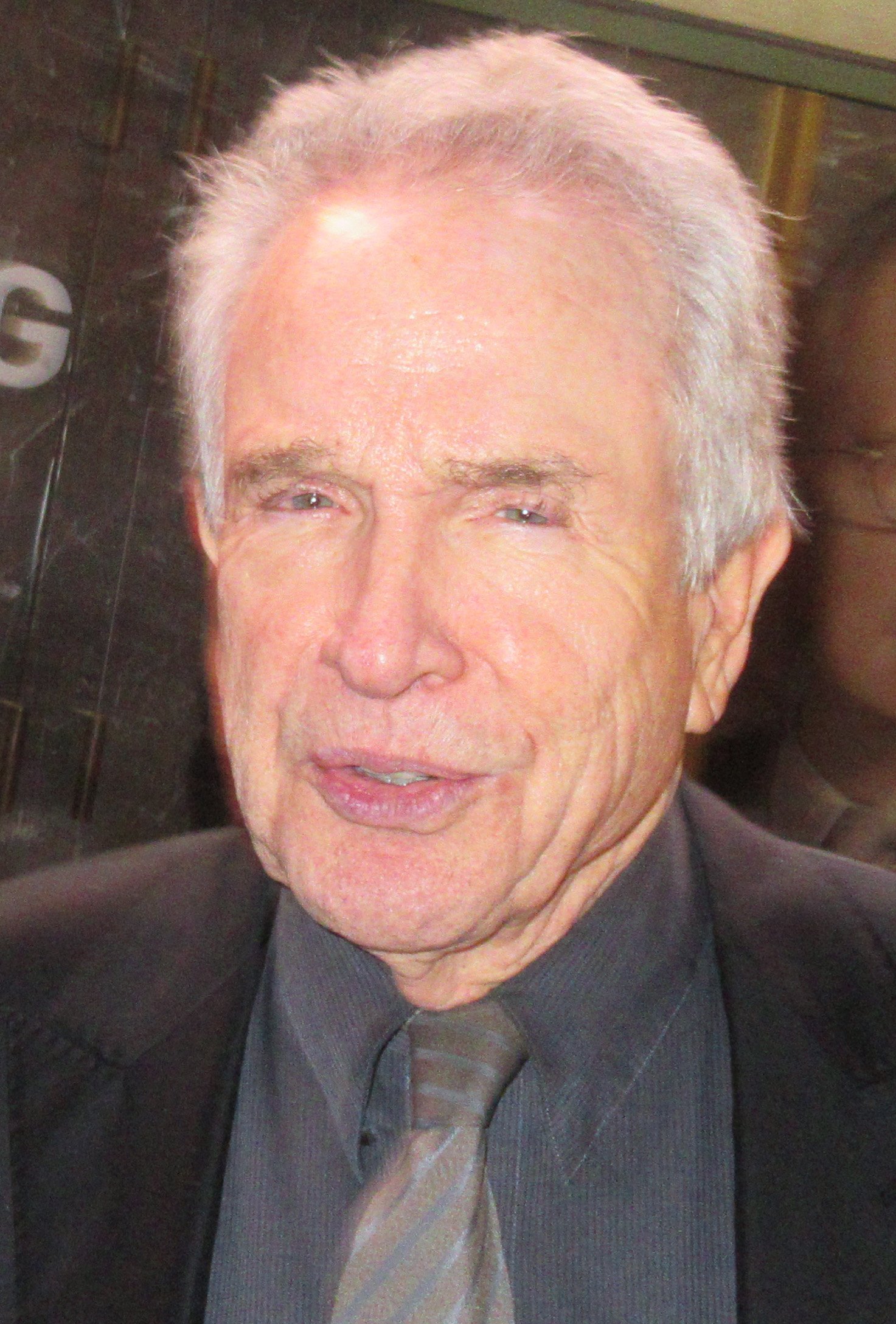Warren Beatty in a close portrait in New York in April 2019, with white hair, wearing a dark suit and tie