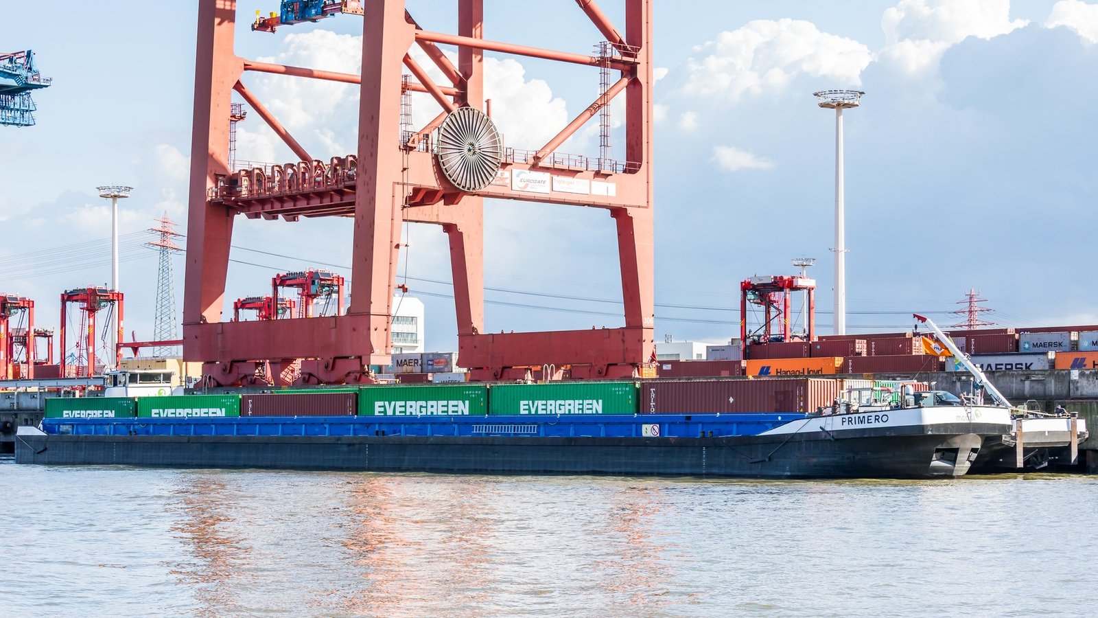 Photograph of a large container ship moored at a container terminal with stacked containers on deck