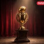Golden football trophy on a pedestal on a theatre stage under a spotlight, with dark red velvet curtains behind